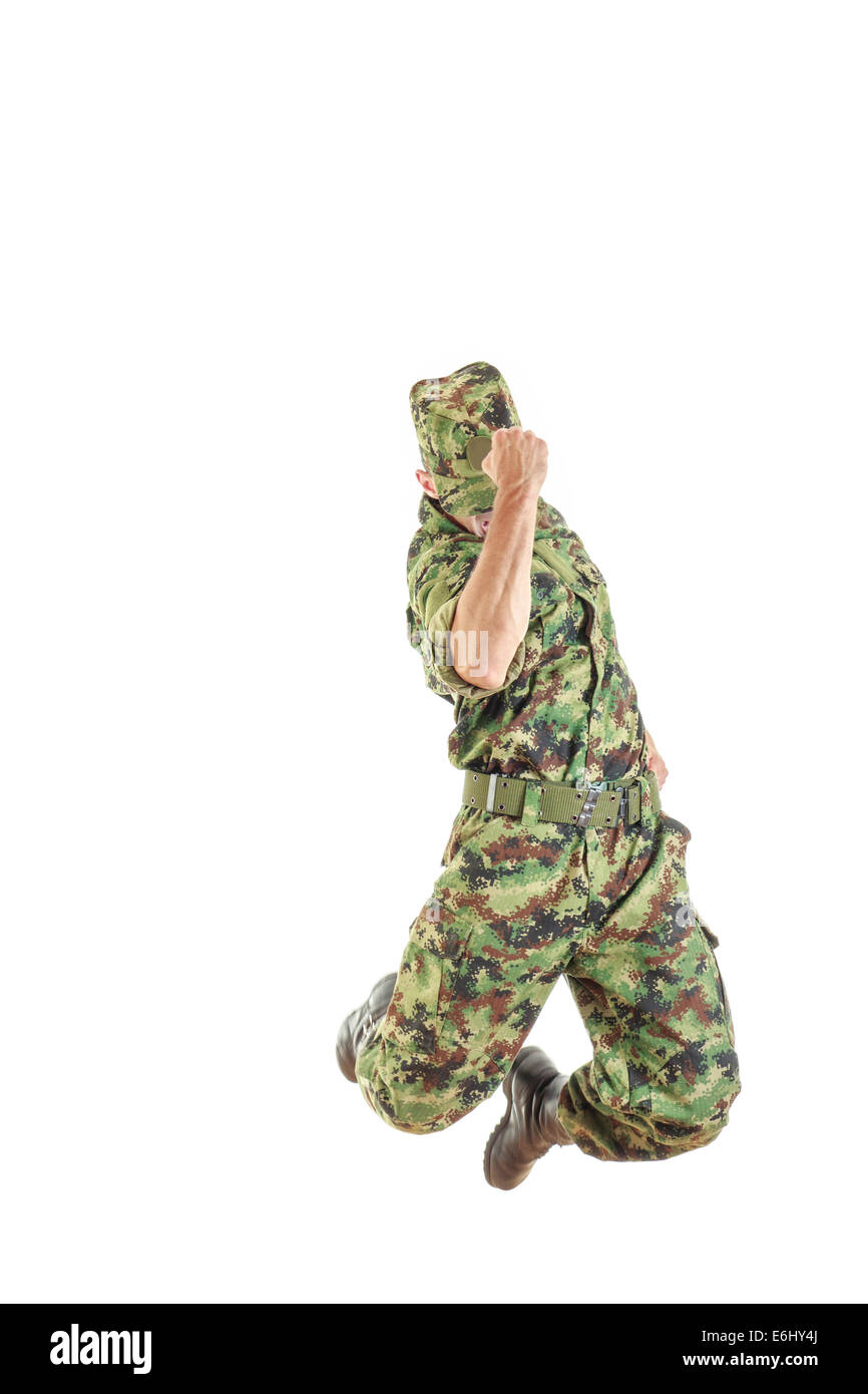 unknown soldier with hidden face in green camouflage uniform and hat jumping up in air with fist sign of success Stock Photo