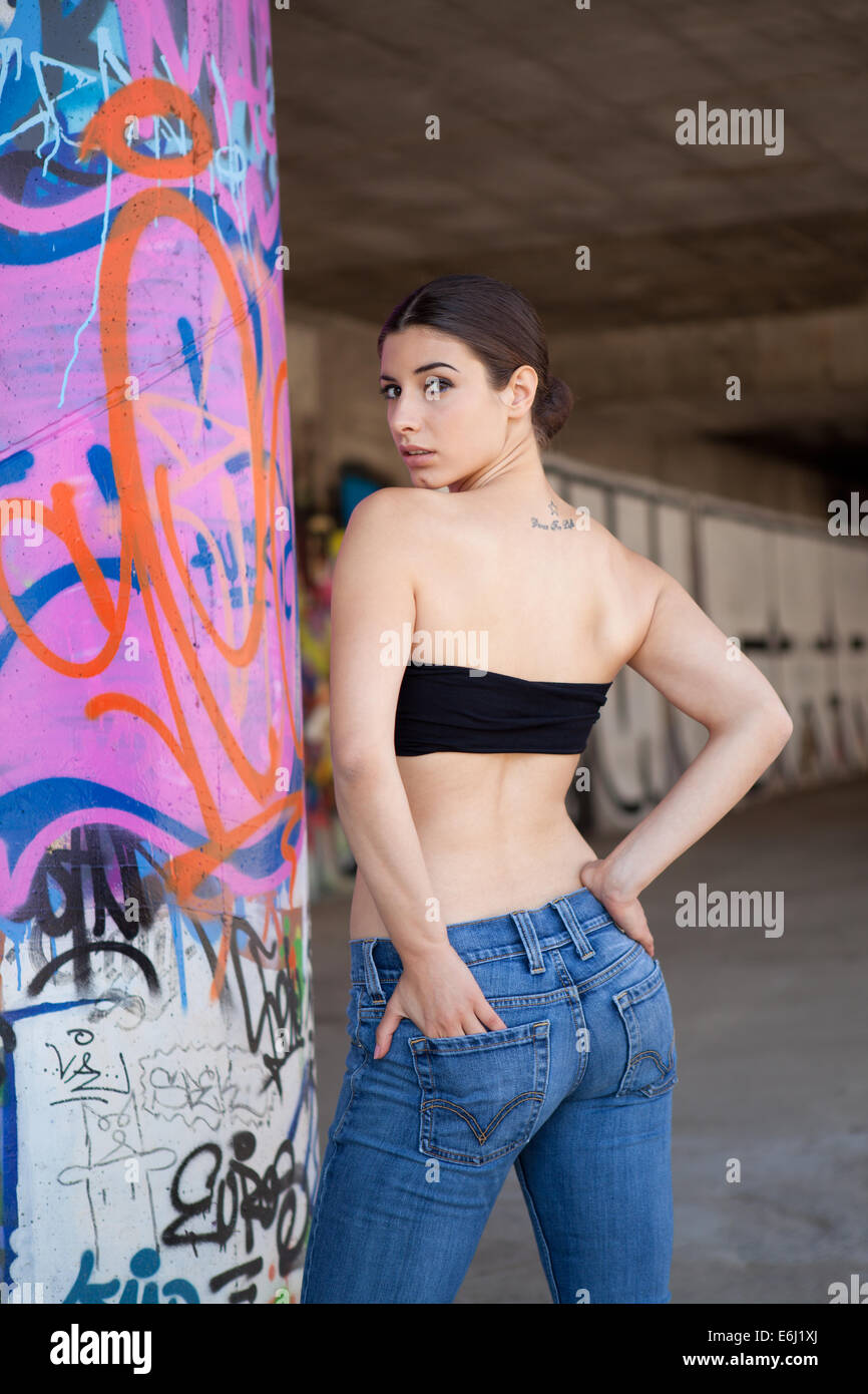 Beautiful girl with black top and jeans in front of graffiti wall. Stock Photo
