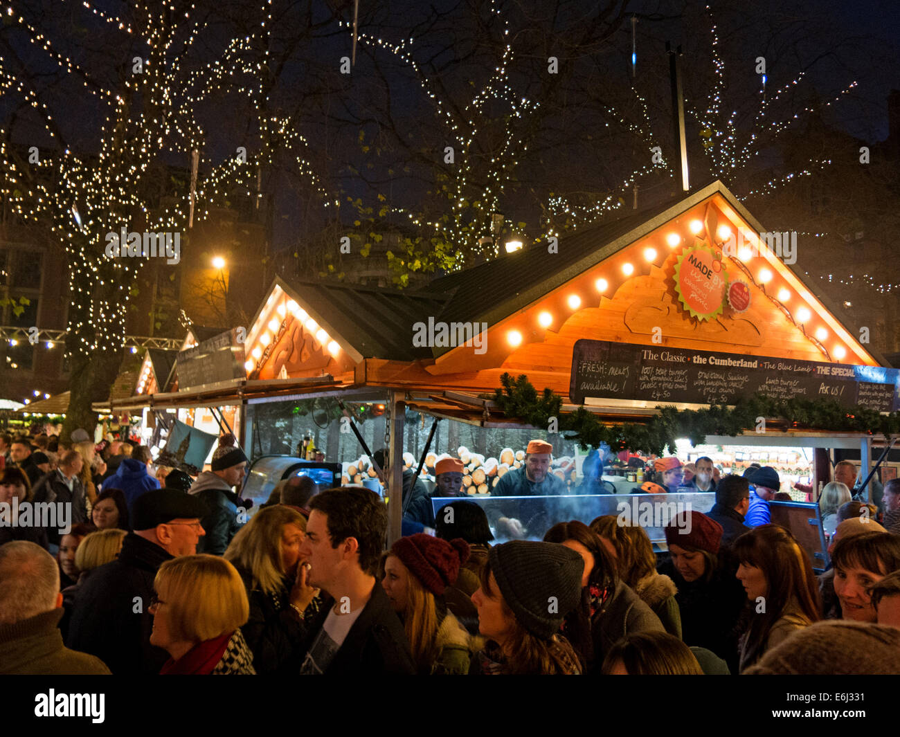 Visitors & shoppers enjoying Manchester Christmas German Markets in Albert Square , December at dusk Stock Photo