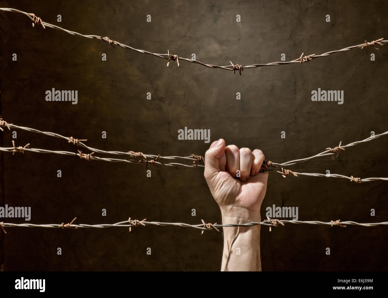 hand behind barbed wire with dark background Stock Photo