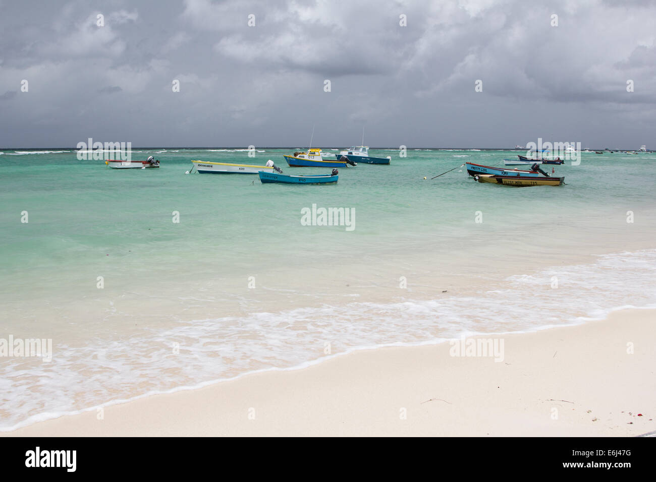 Beach view at St Lawrence Gap Barbados with cloudy sky and small boats in the sea Stock Photo