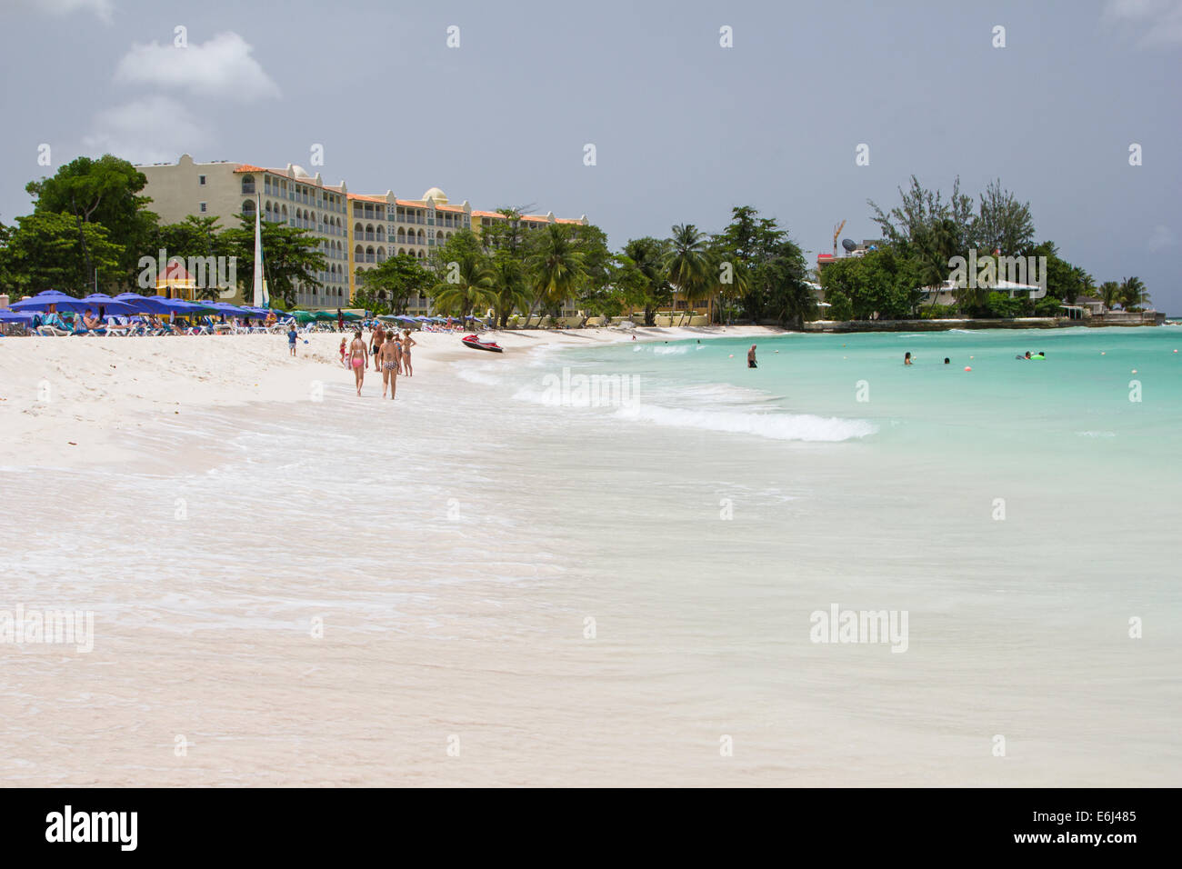 View of Dover Beach Barbados with sea and parasols along the shoreline with hotels in the background Stock Photo