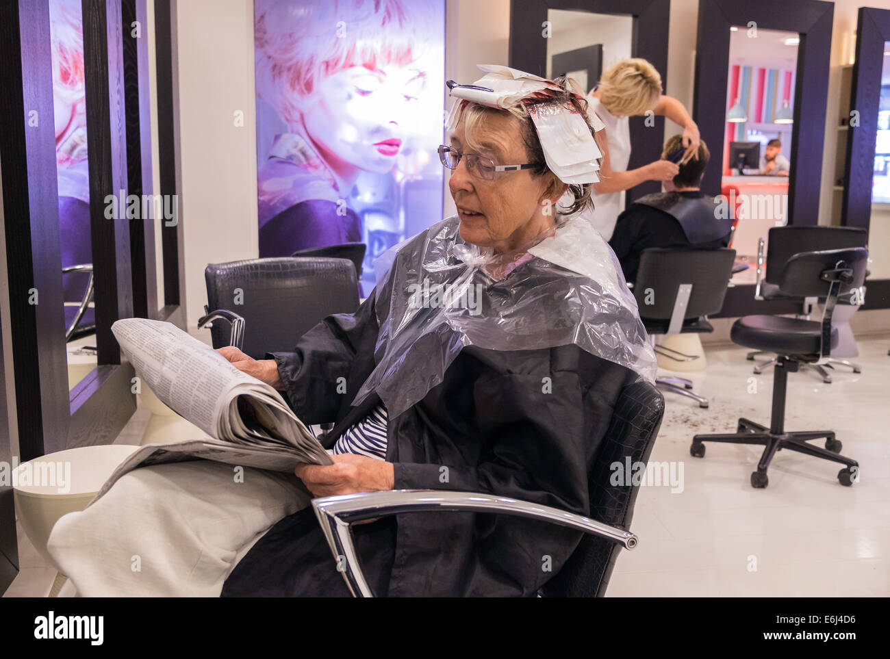 Older Woman In Hair Salon Reading Newspaper While Waiting For Hair