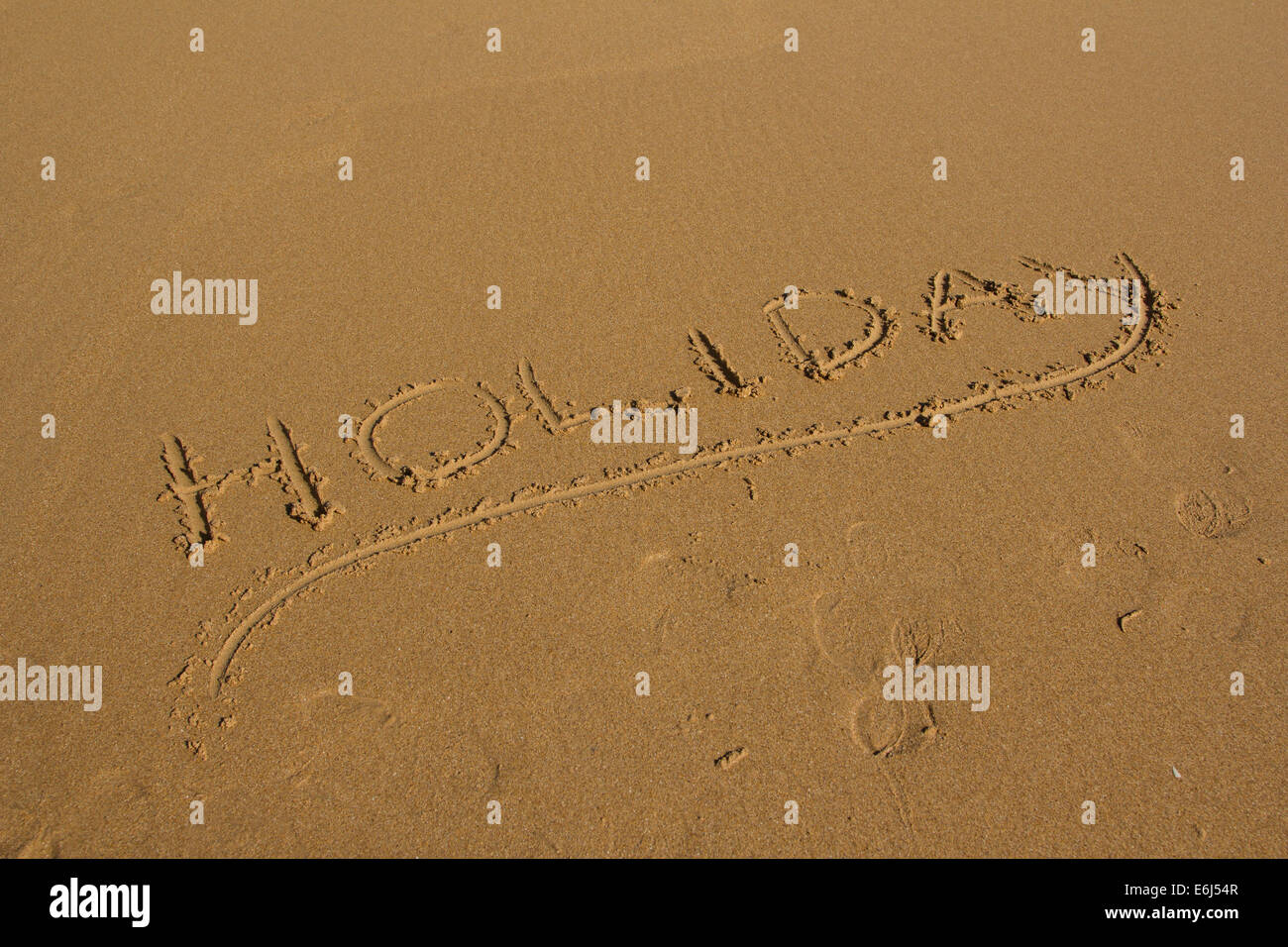 The word holiday written into sand on a beach Stock Photo
