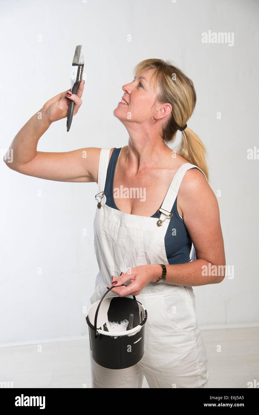 Painting and decorating woman with paint brush and wearing bib and ...