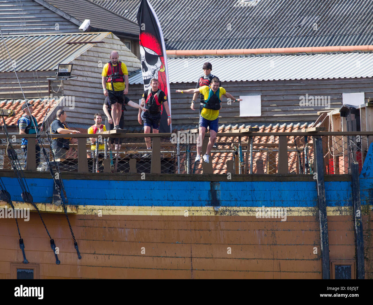 Stockton on Tees, UK. 24th August, 2014. Competitors walking the plank on HMS Endeavour replica  at the 2014 Stockton River Rat Race, a 10km run with land and water obstacles along the banks of the river Tees. Credit:  ALANDAWSONPHOTOGRAPHY/Alamy Live News Stock Photo