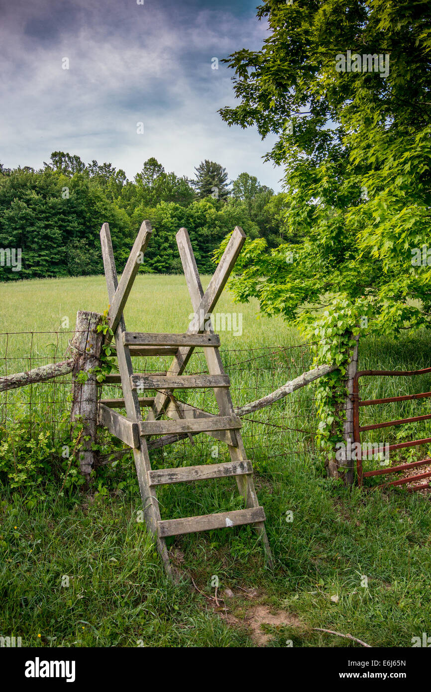 A wooden stile helps hikers  traverse a barbed wire fence guarding farmland along the Appalachian Trail Stock Photo