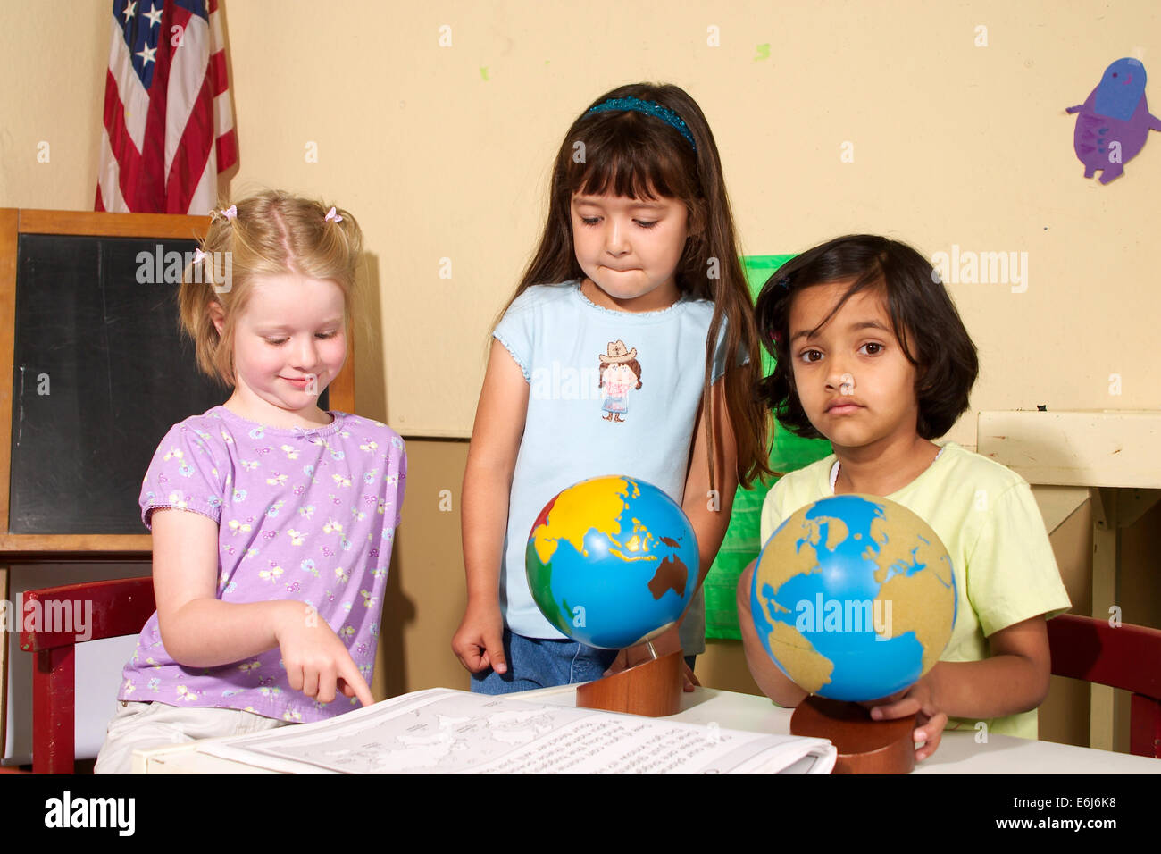 eye contact multi ethnic racial diversity racially diverse multicultural Girls work working together globe map kindergarten school young person people Stock Photo