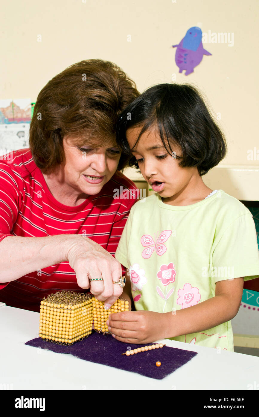 Inter racial interracial Montessori teacher working with 5 year years old olds  age students student girls counting beads arithmetic POV United States Stock Photo
