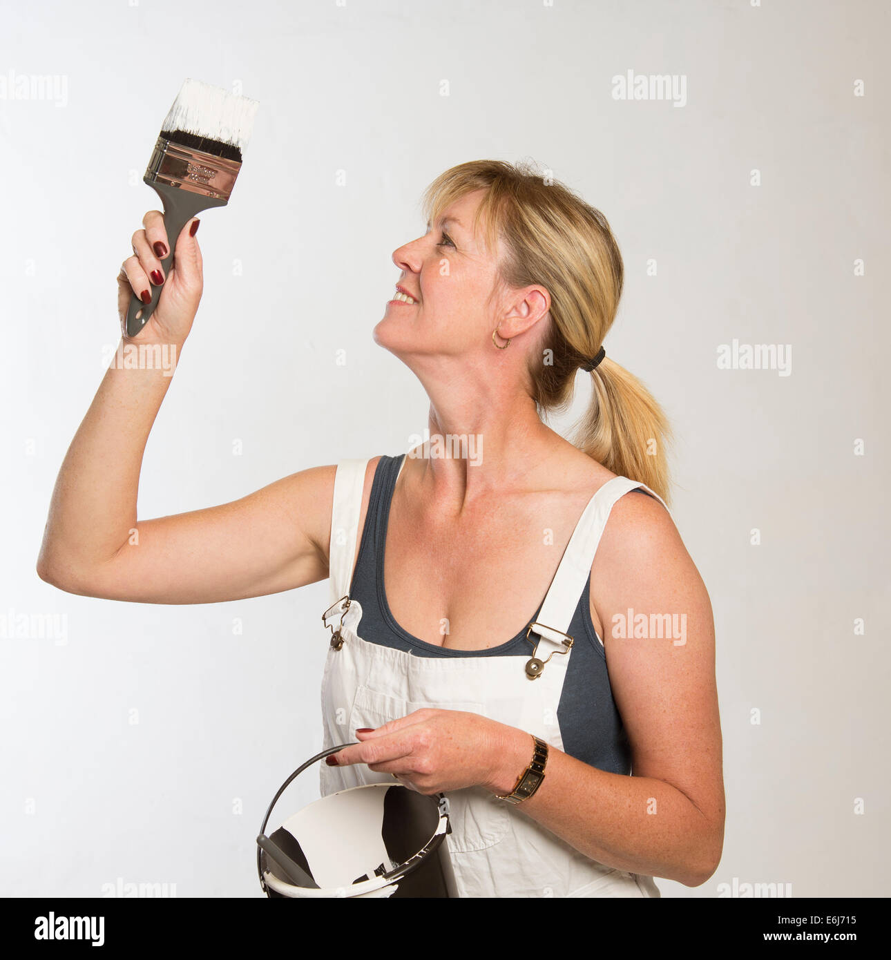 Painting and decorating woman with paint brush and wearing bib and ...