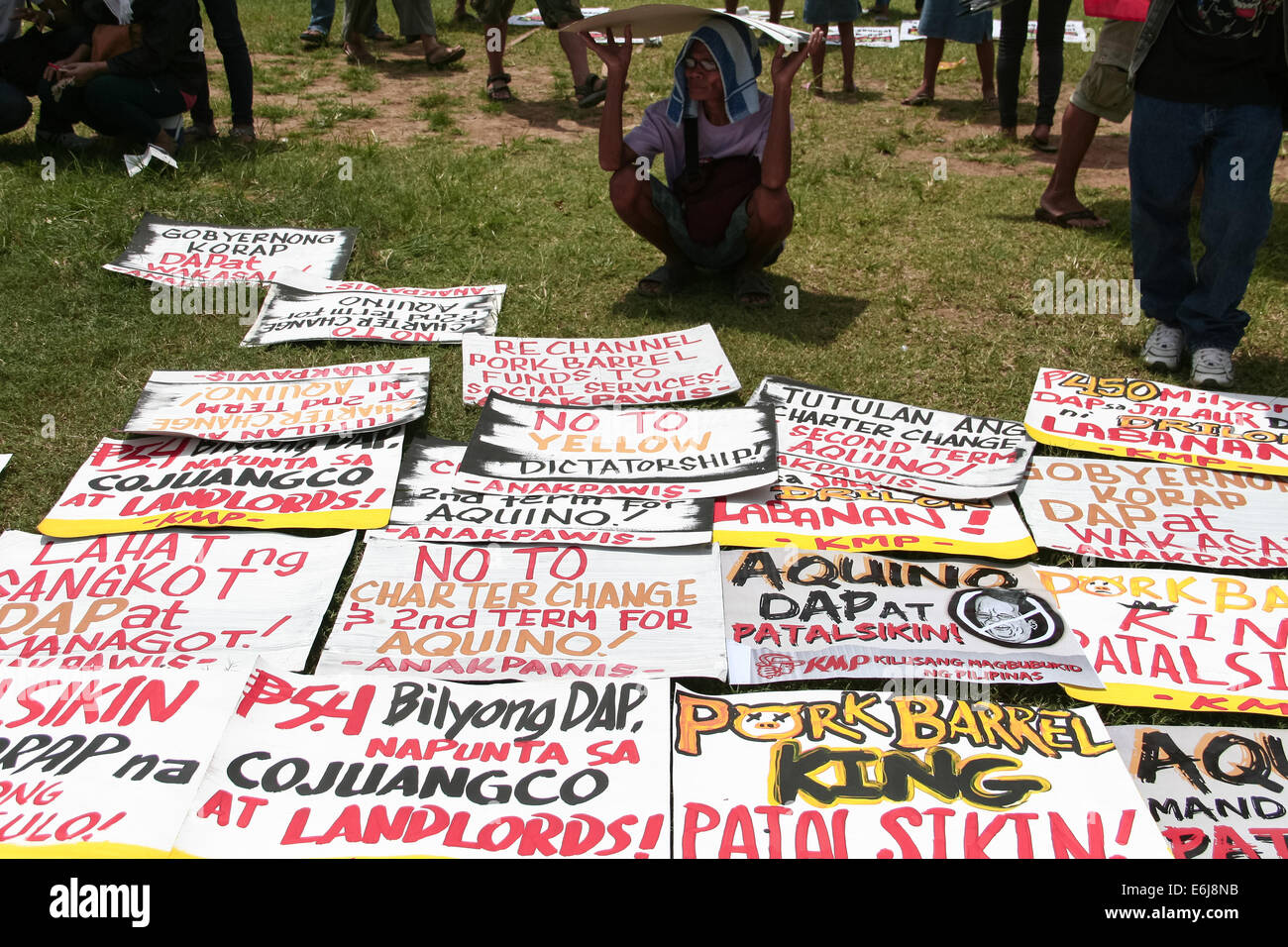 Manila, Philippines. 25th Aug, 2014. An anti Pork Barrel protester shades himself from the sun using one of the posters against President Aquino III at the Quirino Grandstand in Manila. Dubbed as the People's Initiative, protesters flocked to the Quirino Grandstand to sign a petition that stops any Charter Change that could extend the term of the president. They are also calling for the abolishment of the Pork Barrel of politicians. Credit:  J Gerard Seguia/Pacific Press/Alamy Live News Stock Photo