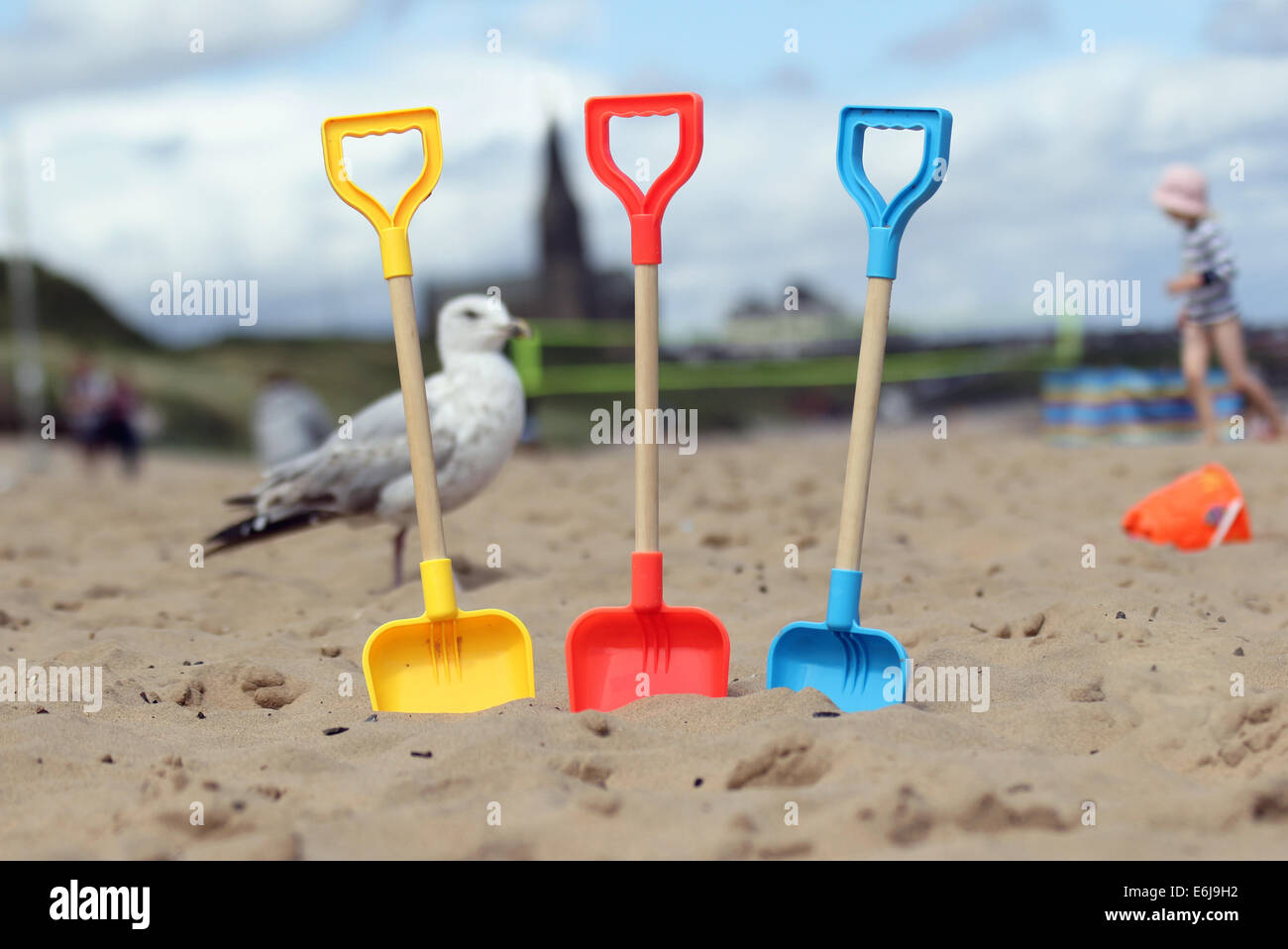 British summer beach scene taken at Tynemouth on the East coast of England featuring sand, spades, gull, child and church Stock Photo