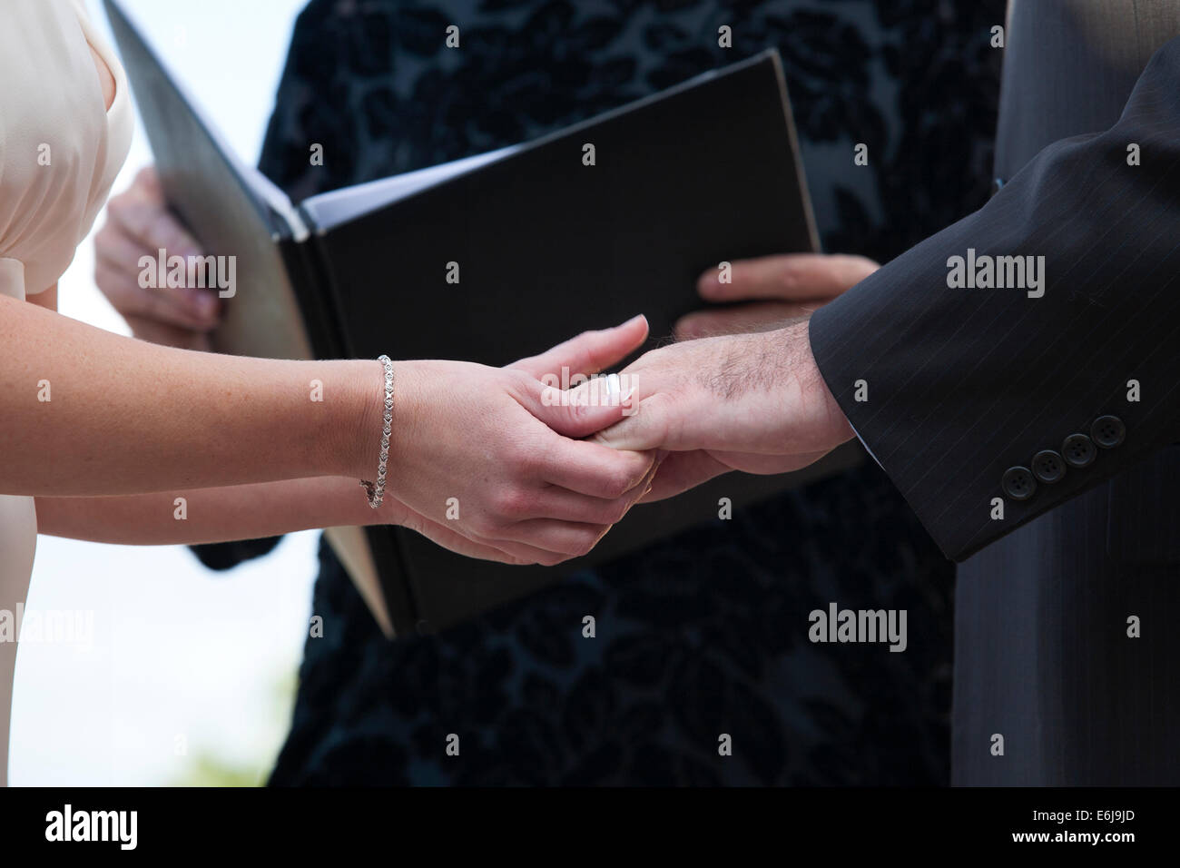 Bride and groom hold hands during their wedding vows. Hands only, no faces. Photo by Janet Worne. Stock Photo