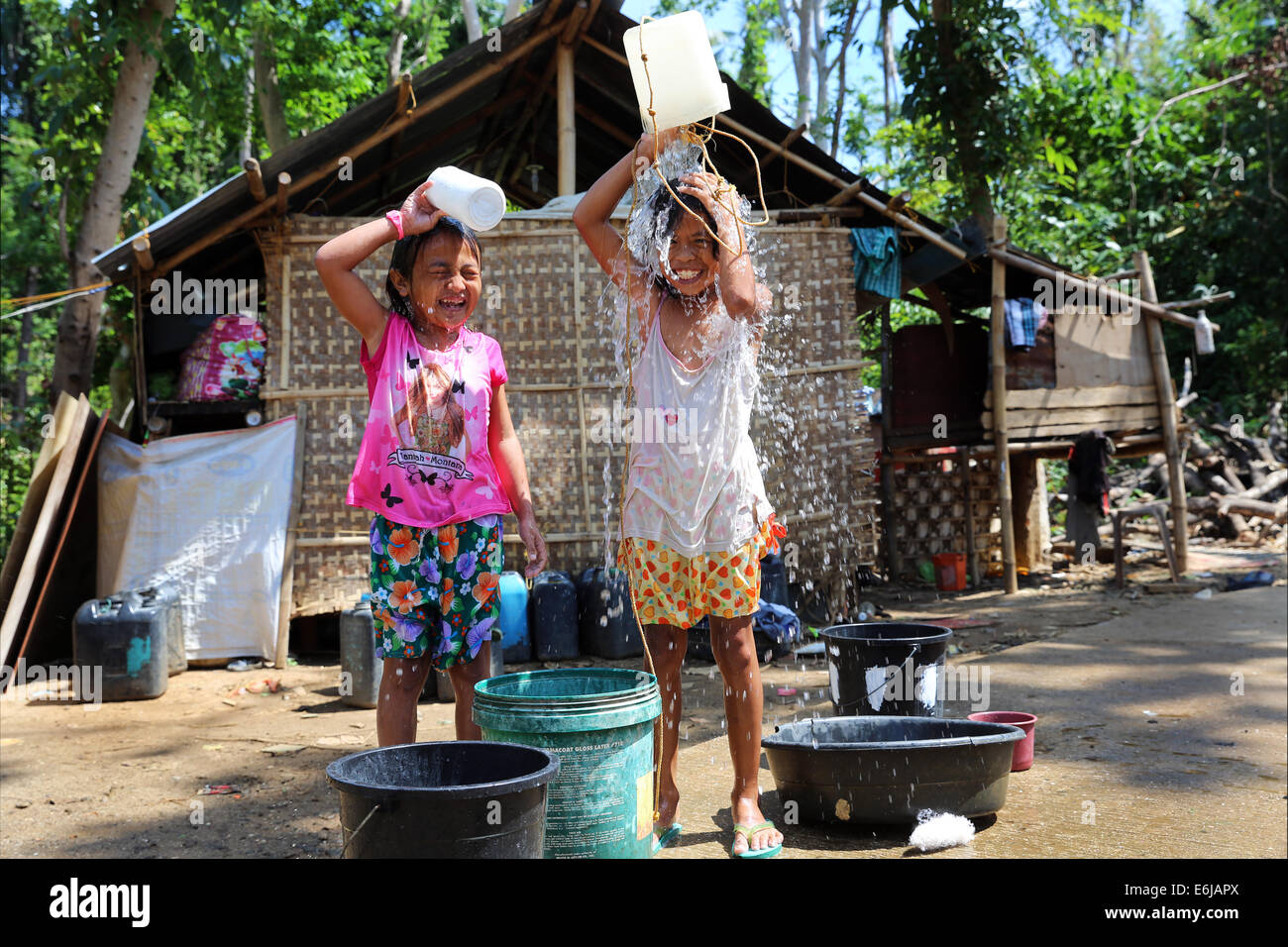 Two children pouring water from a bucket on their heads. The ...