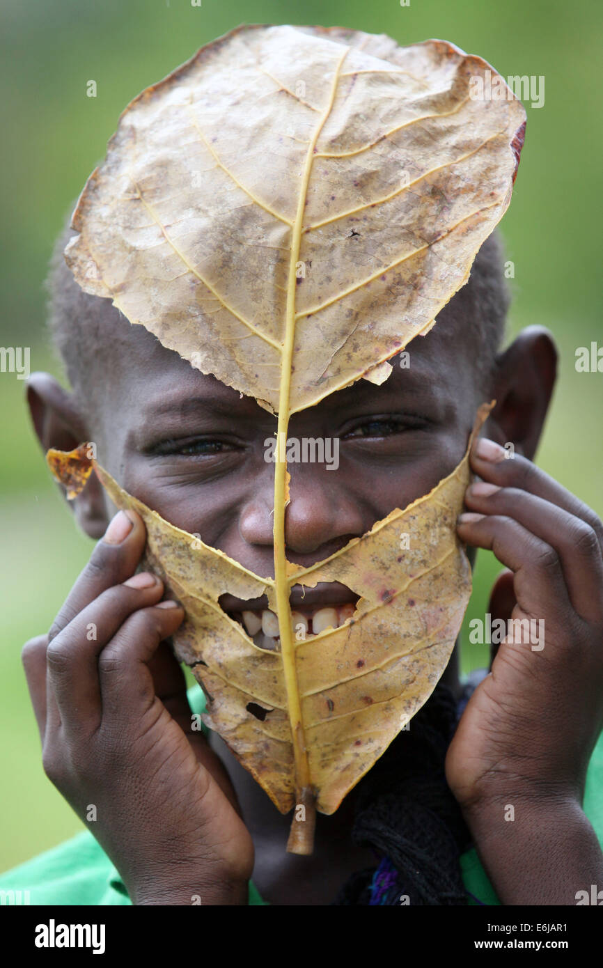 mentally handycaped boy looking behind a dry leaf. Center for handycaped children in Buka, Bougainville, Papua New Guinea Stock Photo