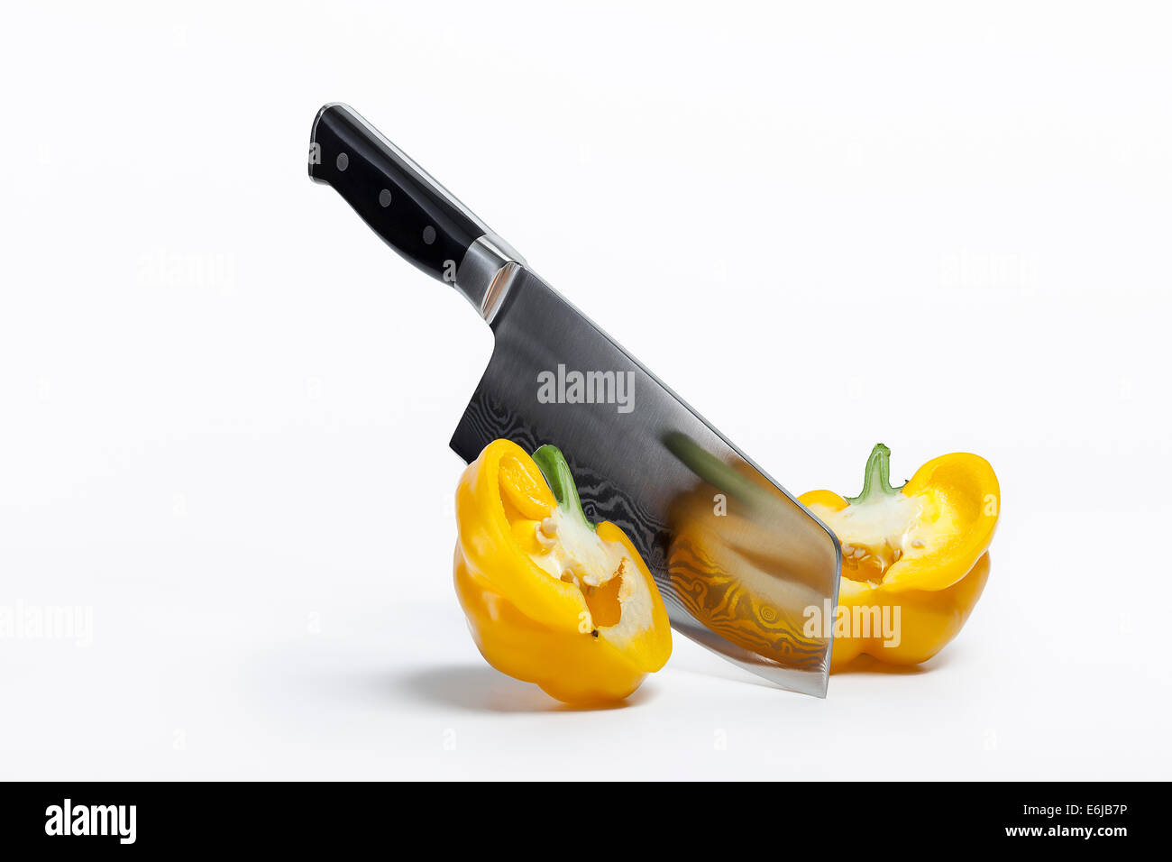 Chefs chopping knife slicing through yellow pepper Stock Photo