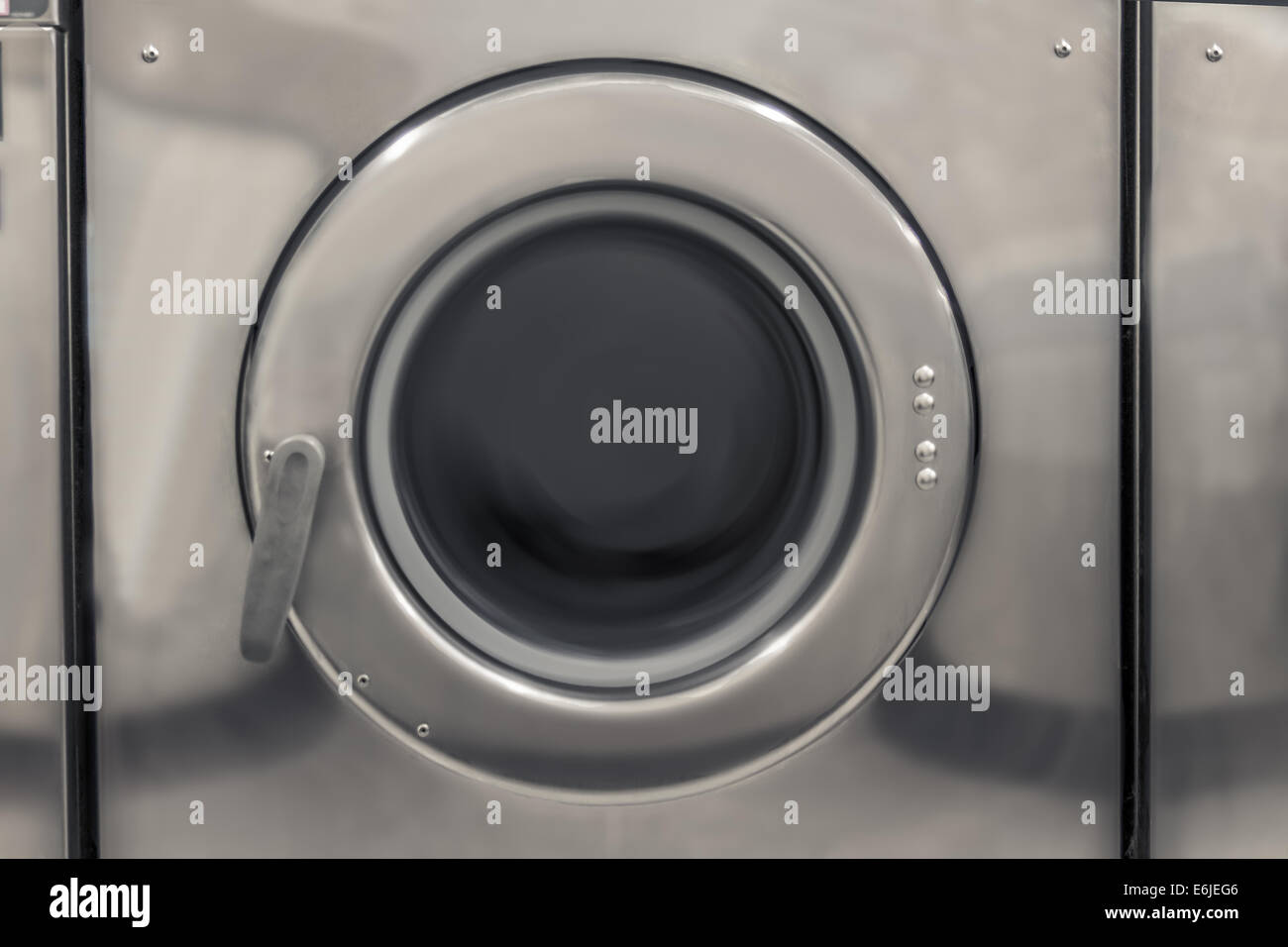 Washing machine at a public laundrette with spinning clothes Stock