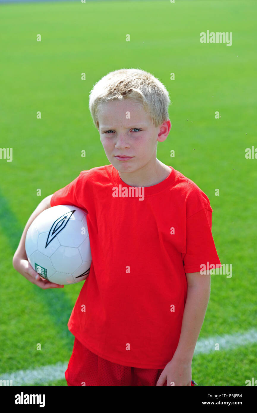 Boy 9 10 11 playing football futball soccer on grassy pitch field sad dejected Stock Photo