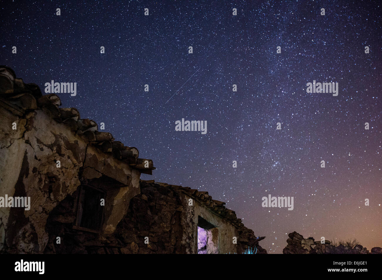 The milky way star formation above old and abandoned building ruins in Spain at Night. Capturing a shooting star Stock Photo