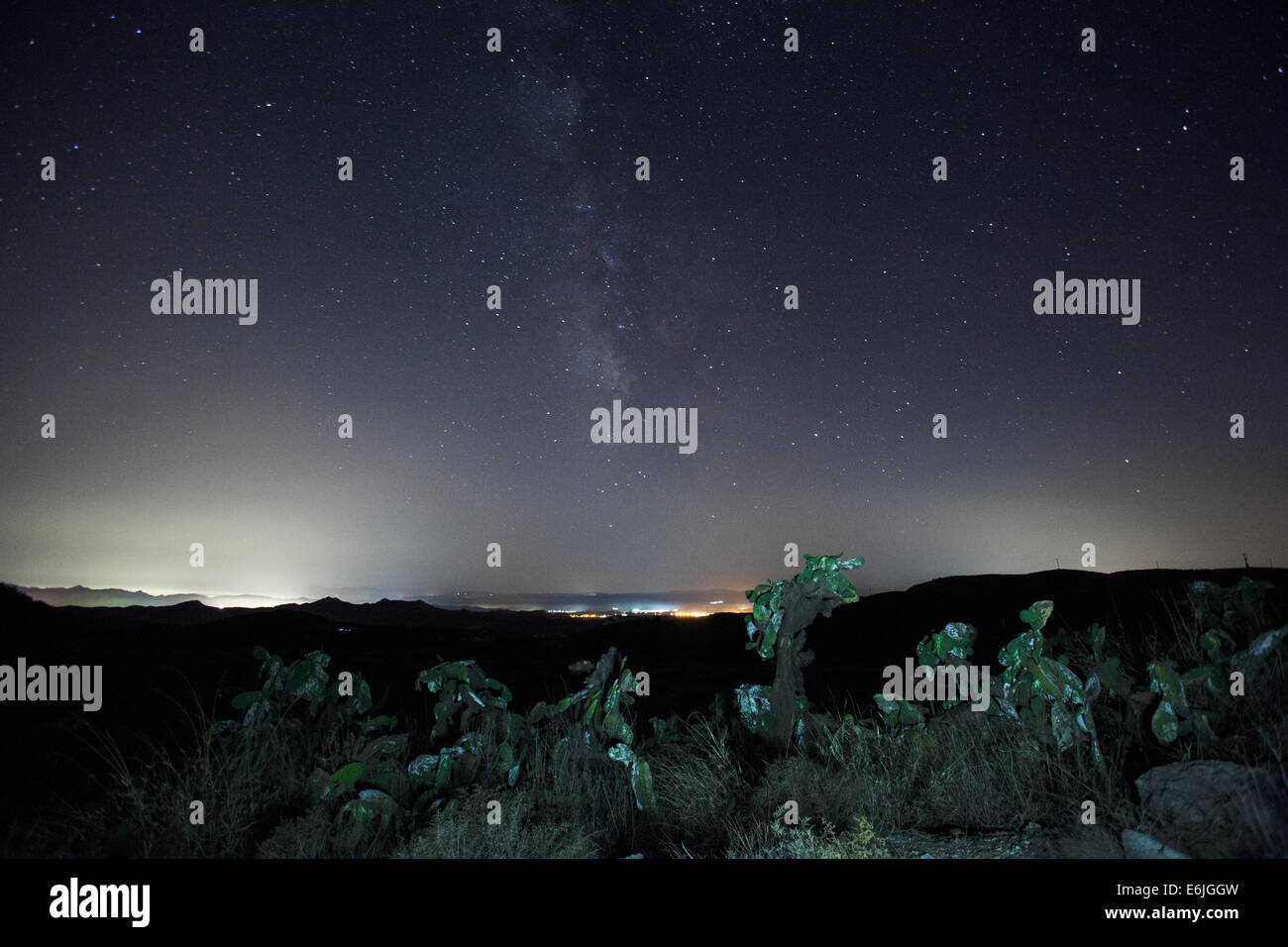 The milky way star formation above cactus's and a small village in Spain at Night. Taken on the Ridgway of a Valley Stock Photo