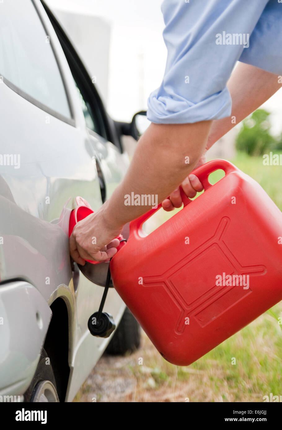 Man refilling his car with funnel and red tank fuel Stock Photo Alamy