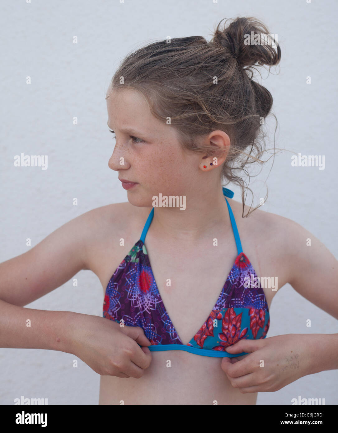 young Caucasian girl wearing a bikini looking to her right adjusting her  bikini top Stock Photo - Alamy