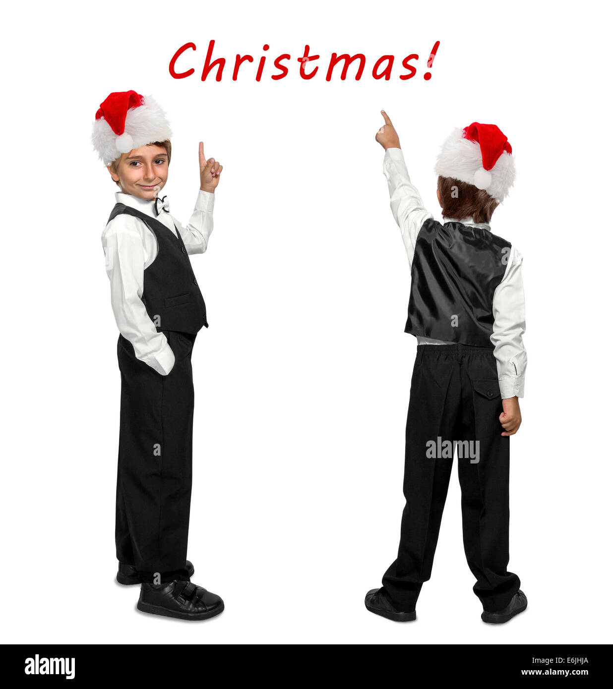 little boy in a tuxedo and  in Santa Claus xmas red hat pointing at wall. Rear view. Stock Photo