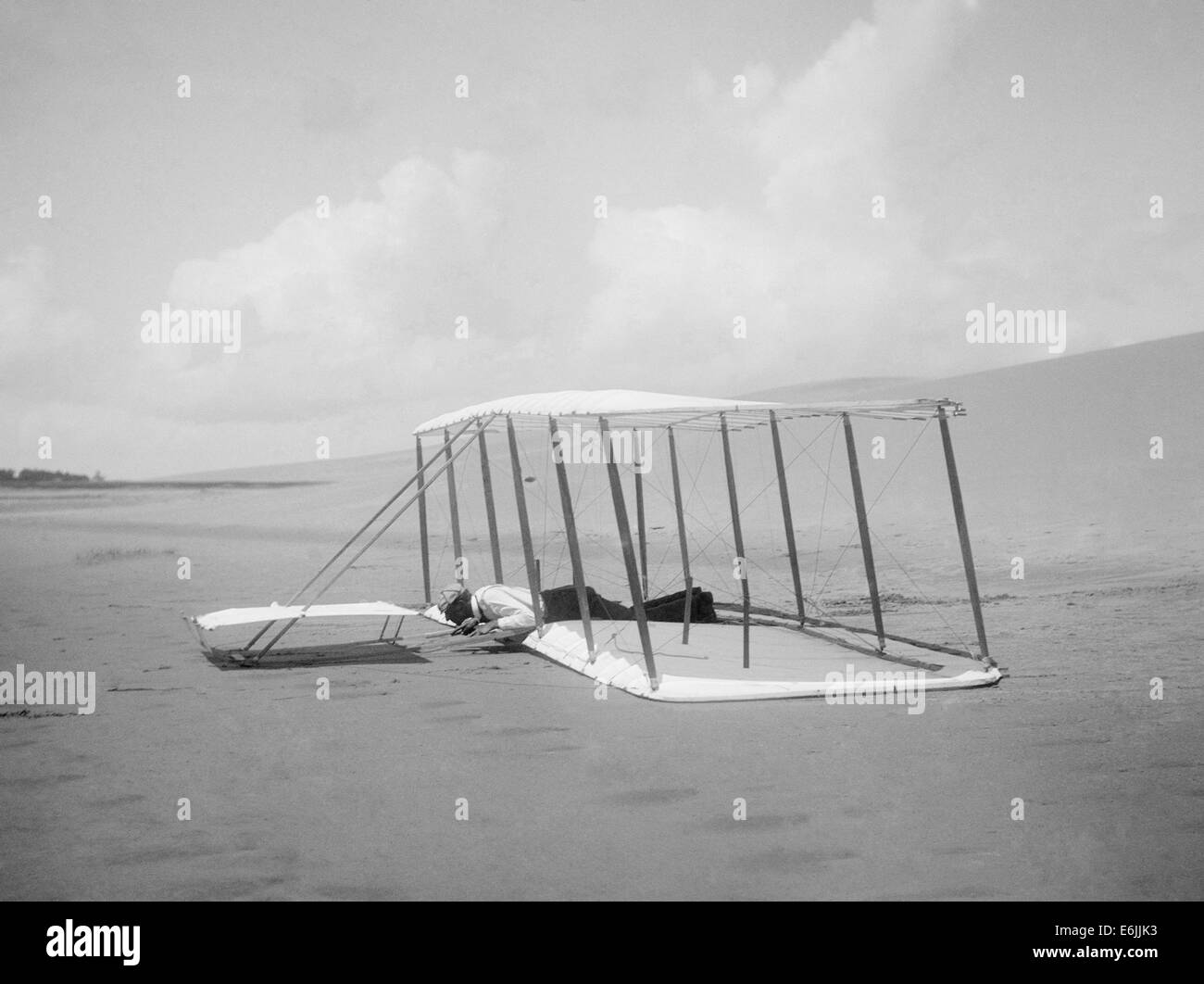 Wilbur Wright after landing the unpowered 1901 glider December 31, 1900 in Kill Devil Hills, North Carolina. Glider skid marks are visible behind it, and marks from a previous landing are seen in front. Stock Photo