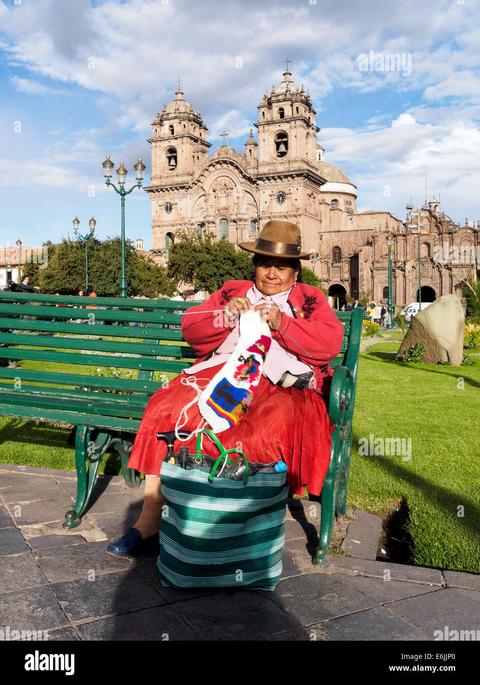 Quechua woman crocheting in plaza de Armas and the Iglesia de la Compañía de Jesus in the background - Cusco, Peru Stock Photo