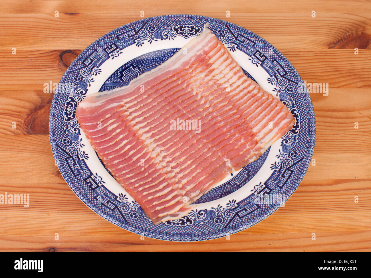streaky bacon in the blue plate on wooden table Stock Photo