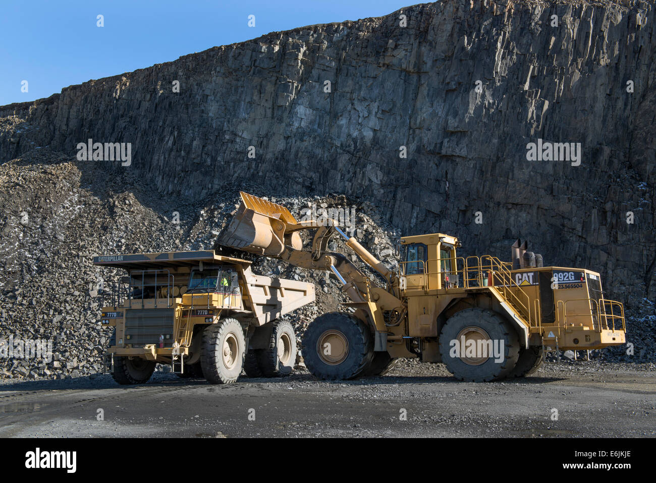100 ton Caterpillar 7770D truck and 992G wheel loader hauling basalt trap rock mined from basalt ridge at the Tilcon quarry. Stock Photo