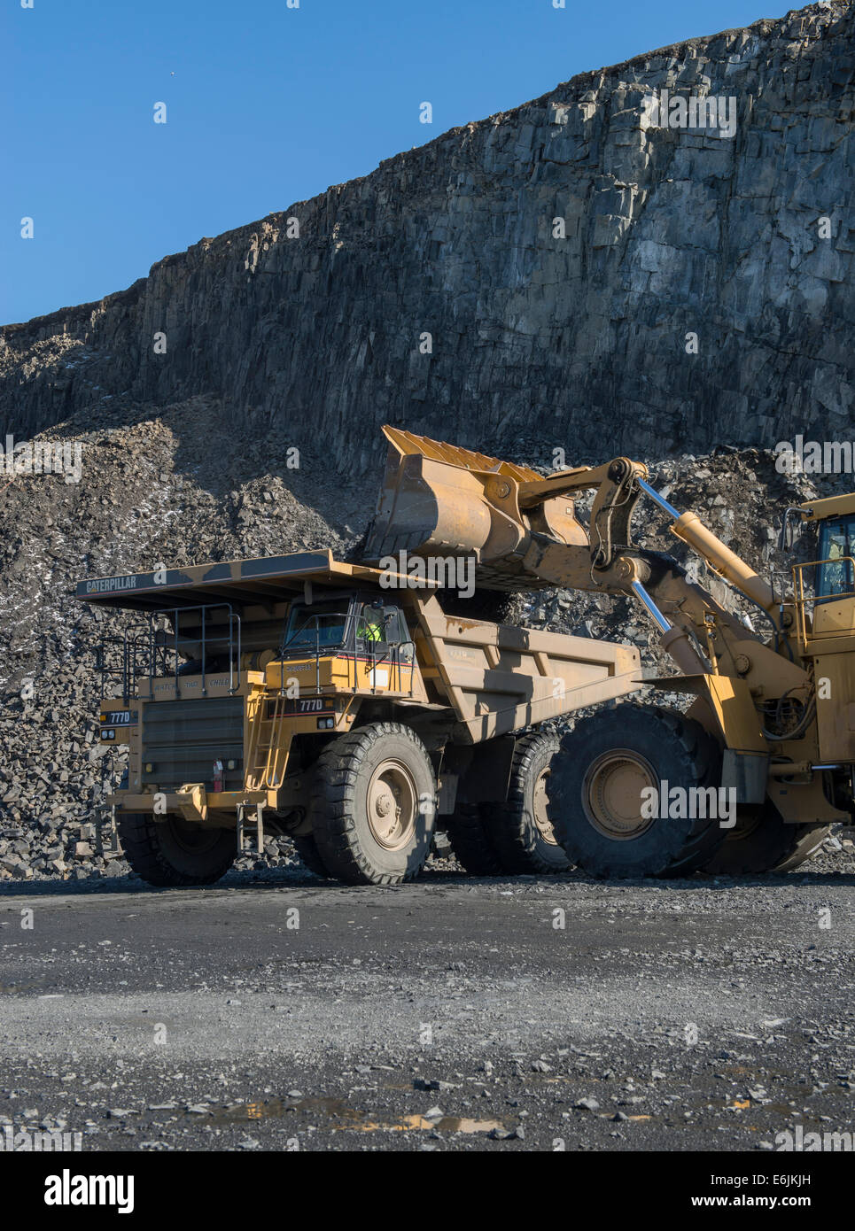 100 ton Caterpillar 7770D truck and 992G wheel loader hauling basalt trap rock mined from basalt ridge at Tilcon quarry. Stock Photo