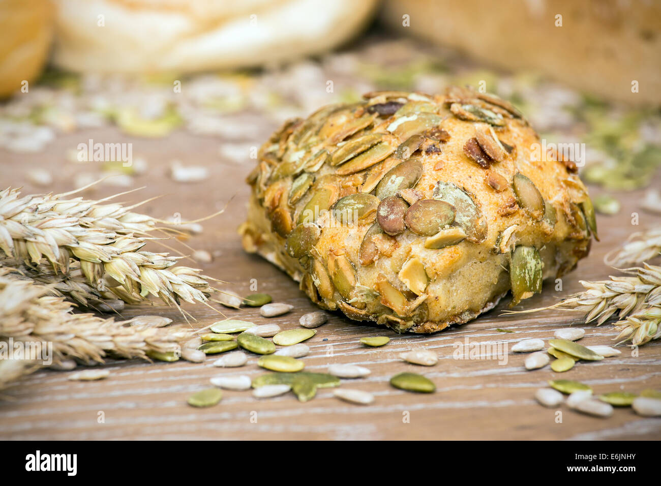 Freshly baked roll with pumpkin seeds on wooden table Stock Photo