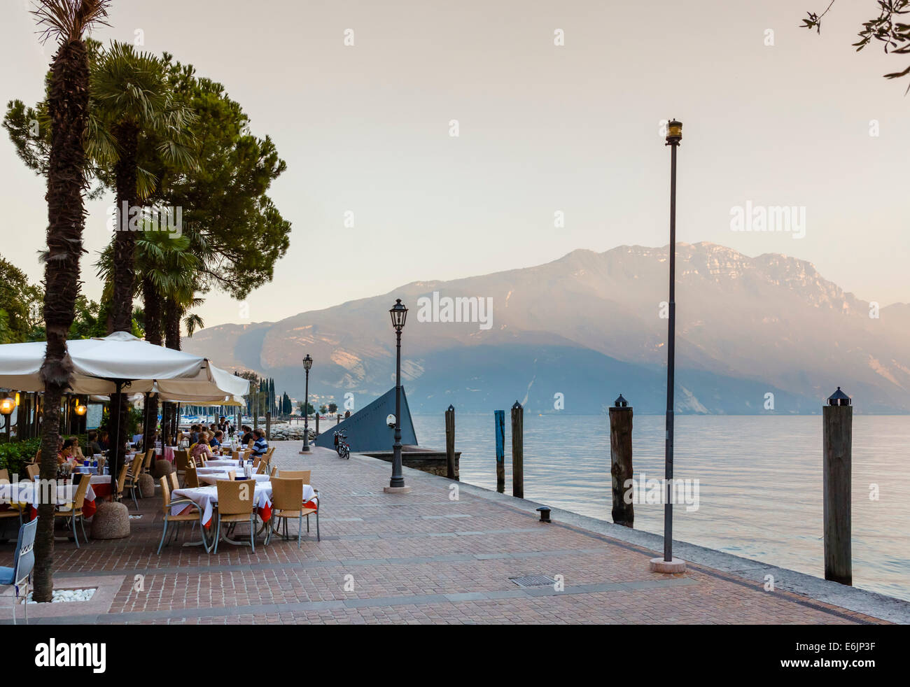 Restaurant on the harbourfront at sunset in the old town, Riva del Garda, Lake Garda, Trento, Italy Stock Photo