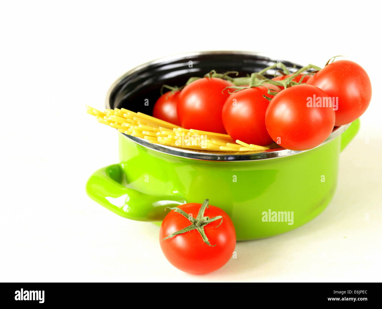green pot full of tomatoes and pasta Stock Photo