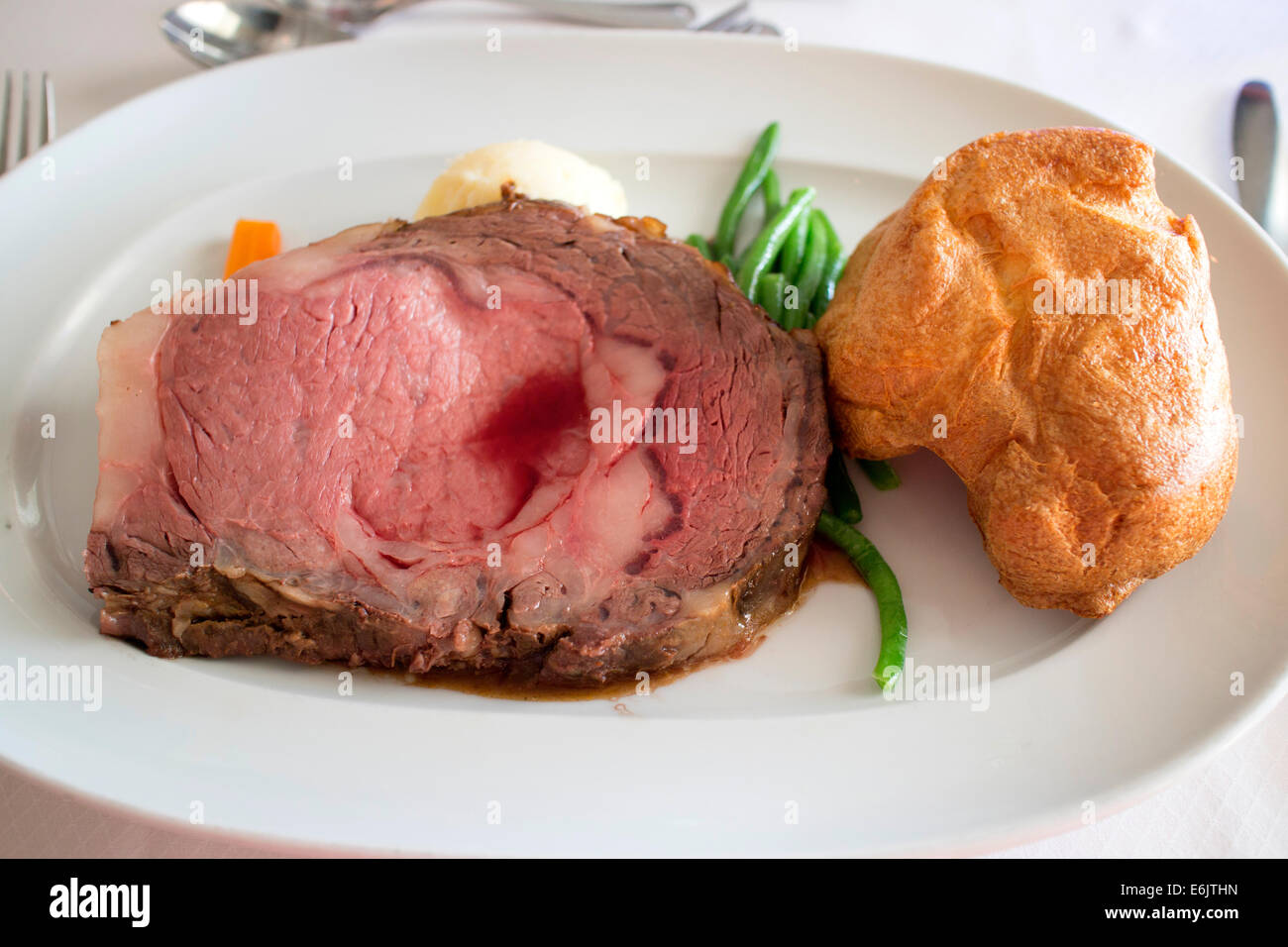 Aged prime rib of beef with mashed potatoes green beans and Yorkshire pudding cooked medium rare Stock Photo