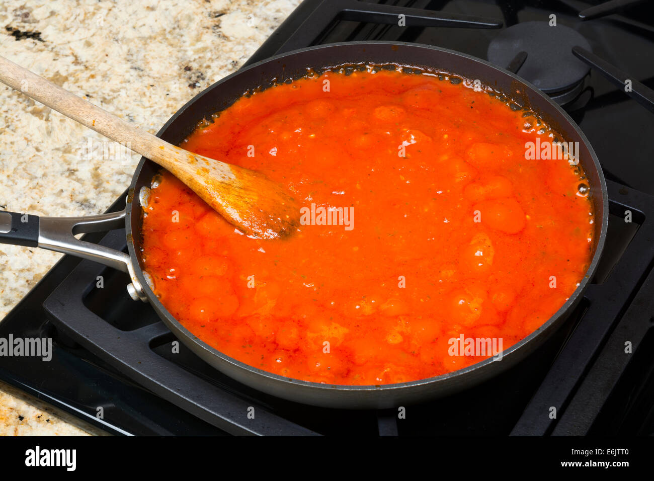 Fresh marinara spaghetti sauce with spices simmering on a gas stove before being added to the pasta. Stock Photo
