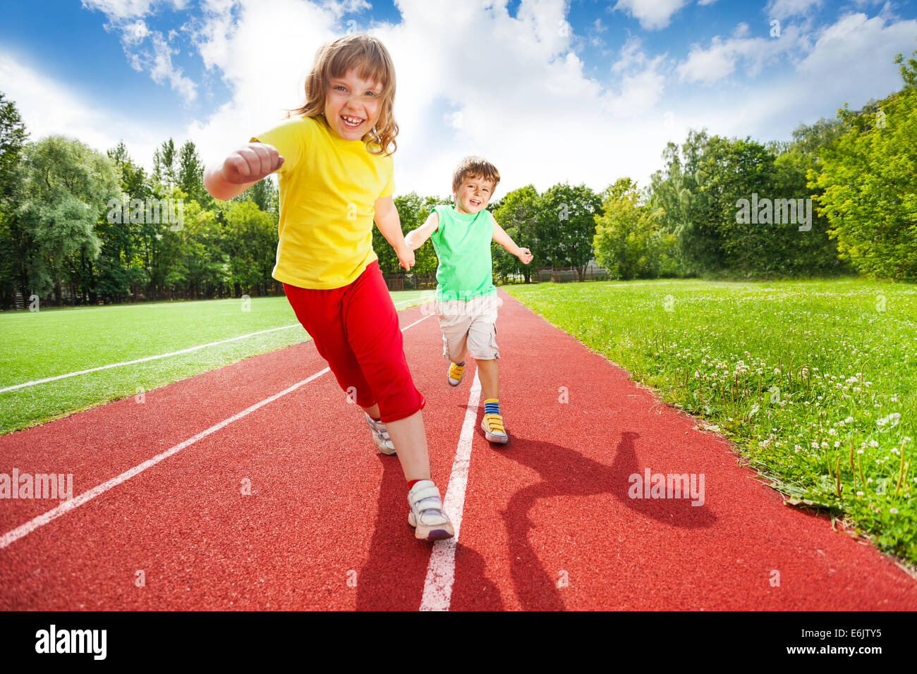 Two children holding hands running together Stock Photo