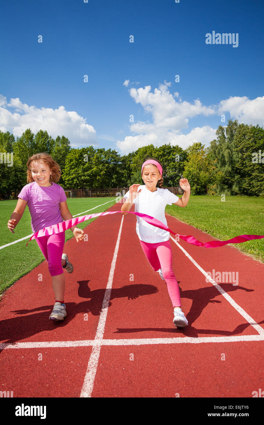 Running girls try reaching the ribbon excited Stock Photo