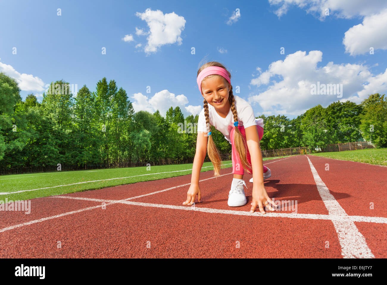 Smiling girl in position on knee ready to run Stock Photo