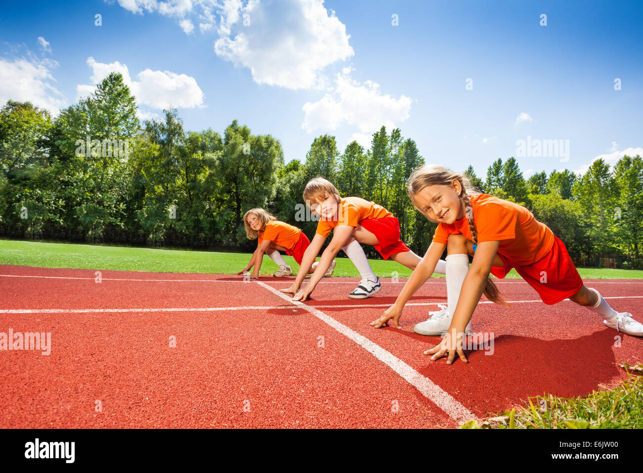 Children on bending knees in row ready to run Stock Photo