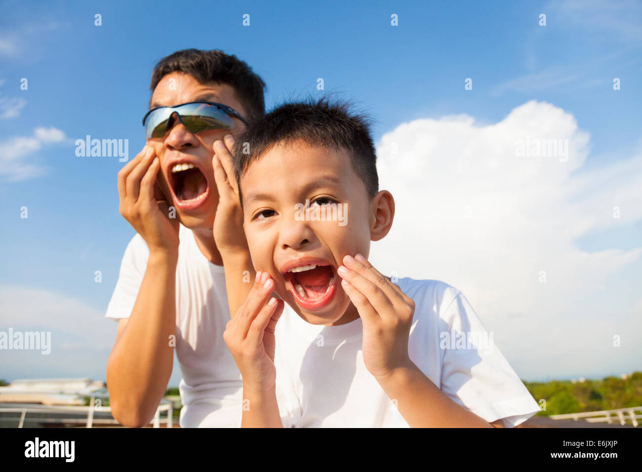father and son making a grimace together in the park Stock Photo