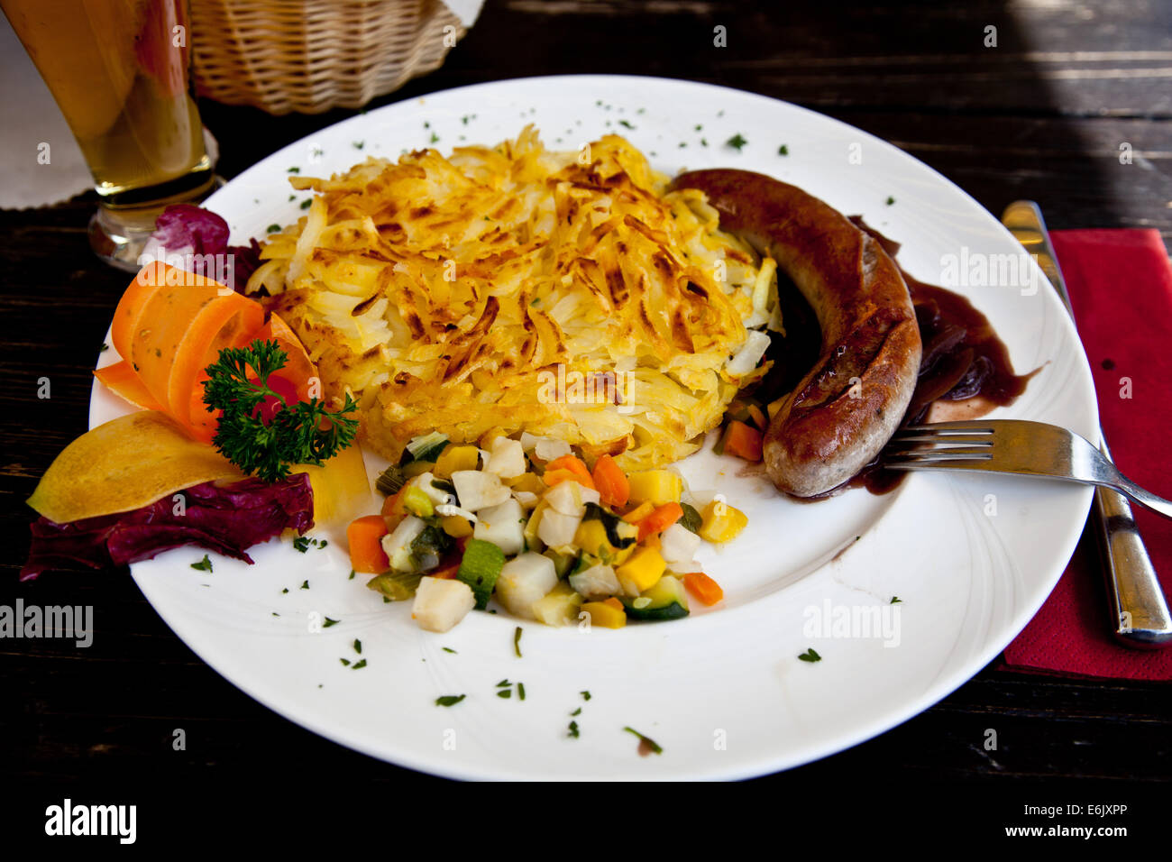 Hearty Swiss Alpen fare incuding pork Schnitzel with roasted potatos and vegetables garnished with cabbage, carrots, parsely. Stock Photo