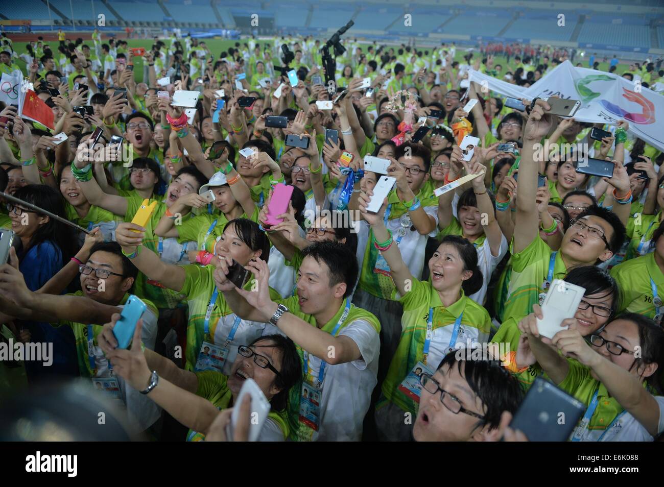 Nanjing, China's Jiangsu Province. 25th Aug, 2014. Volunteers take selfies during a farewell party in the Nanjing Olympic Sports Center Stadium during the Nanjing 2014 Youth Olympic Games in Nanjing, capital of east China's Jiangsu Province, on Aug. 25, 2014. © Shen Peng/Xinhua/Alamy Live News Stock Photo