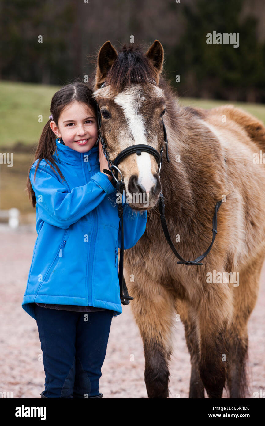 Girl standing beside a pony, dun, with a bridle, Tyrol, Austria Stock Photo