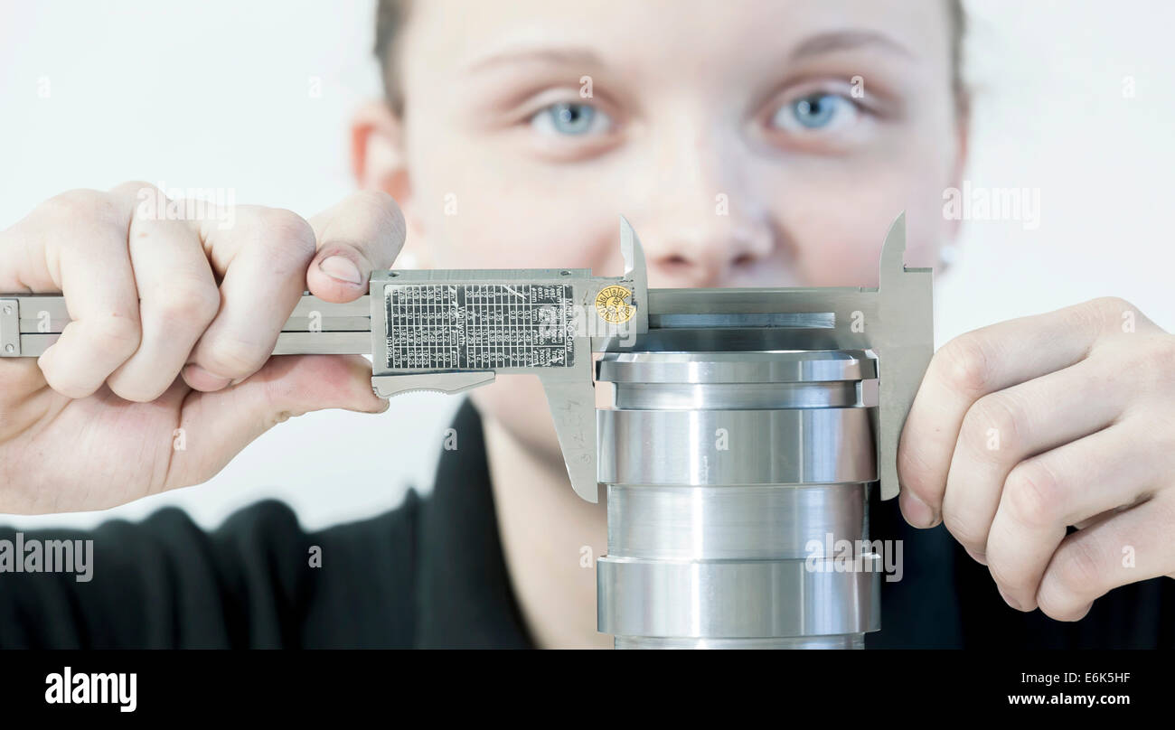 A female cutting machine operator trainee is measuring a casing with a caliper, training center of the engine and turbine Stock Photo