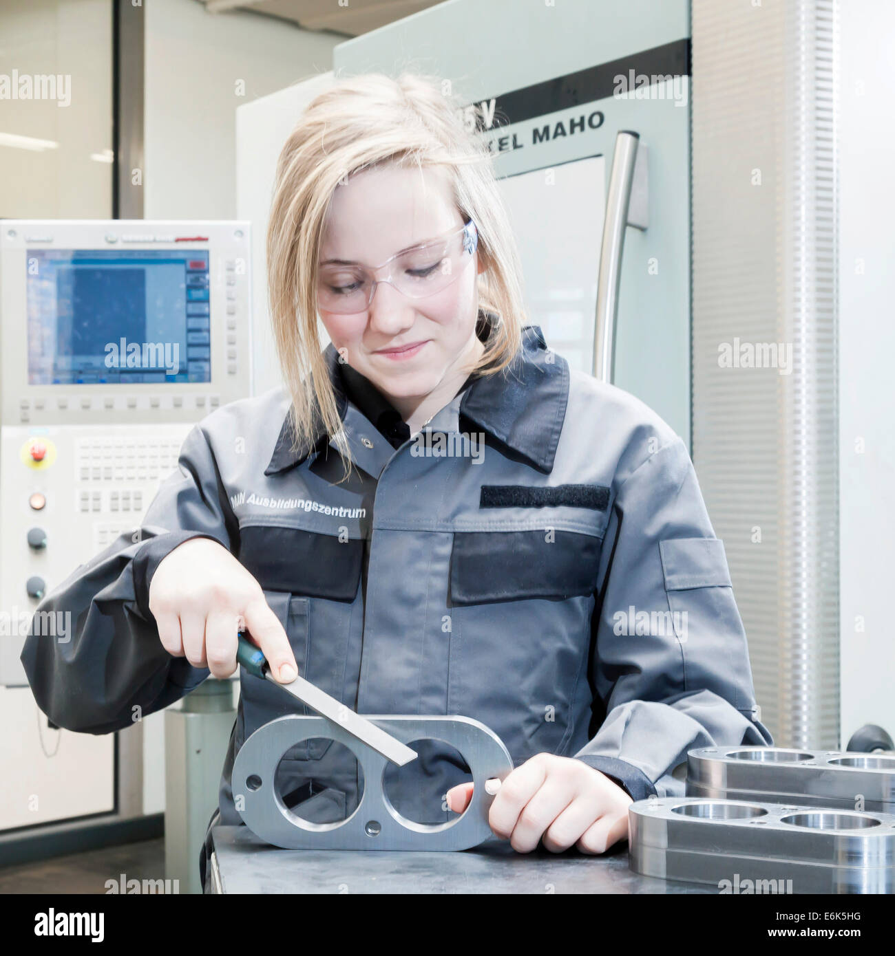 A female cutting machine operator trainee is deburring a component, training center of the engine and turbine manufacturer MAN Stock Photo