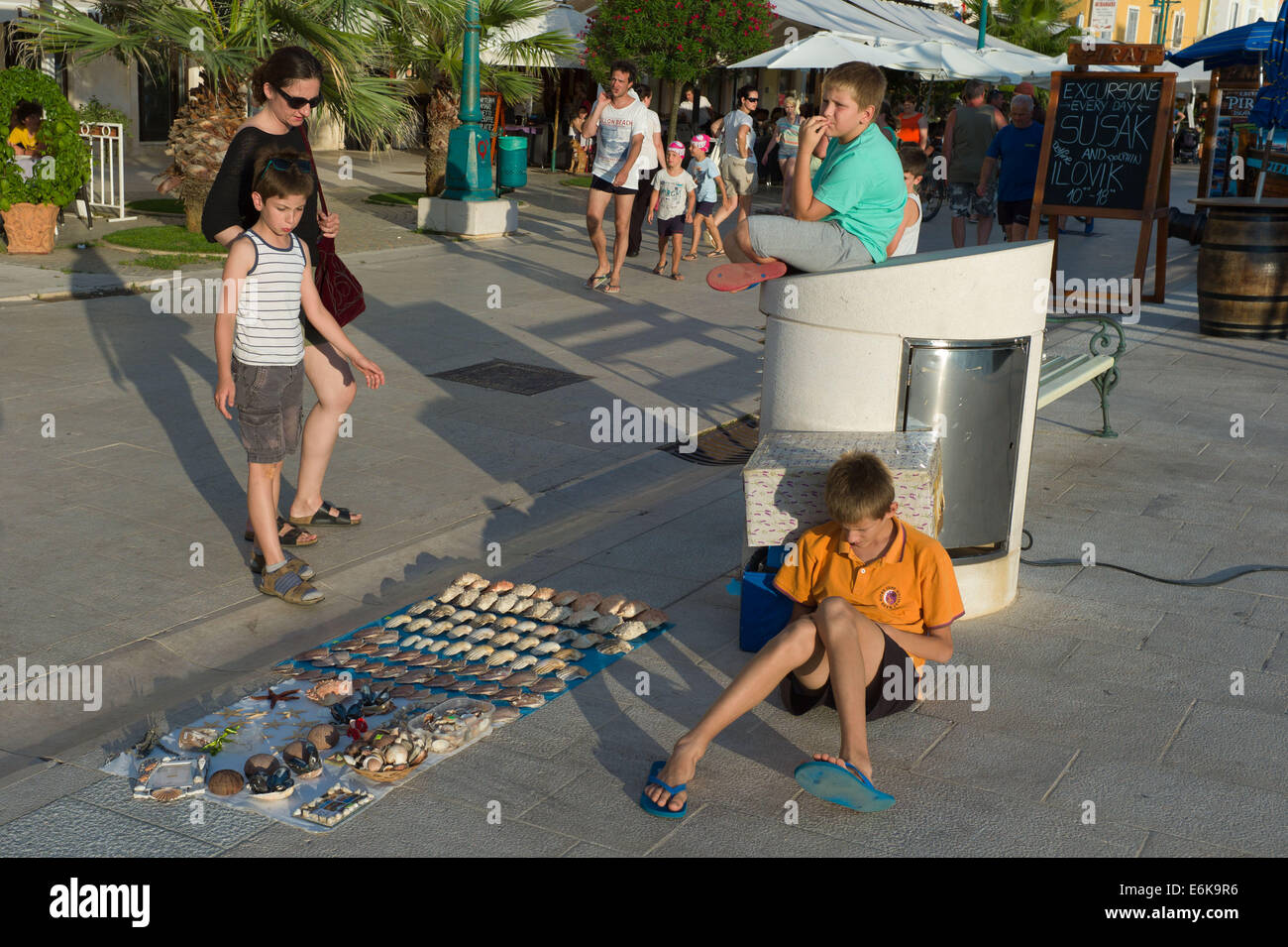 Child selling sea shells to tourist on the harbour in Mali Losinj town, Losinj Island Croatia Stock Photo