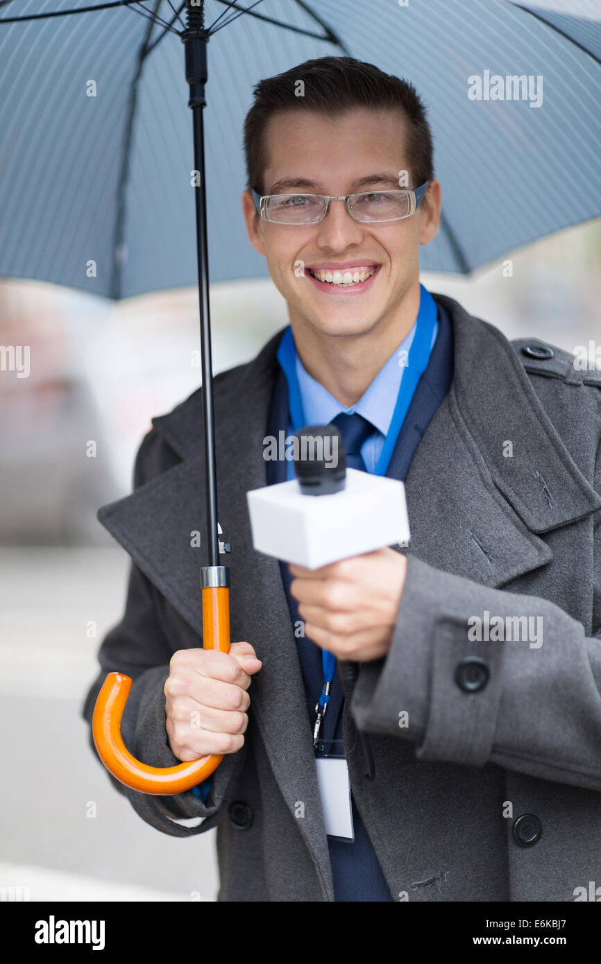 handsome young journalist working outdoors in the rain Stock Photo