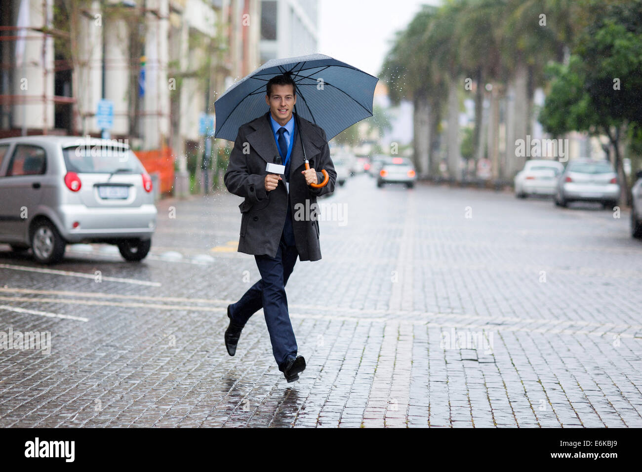 young news correspondent rushing for breaking news in raining day Stock Photo